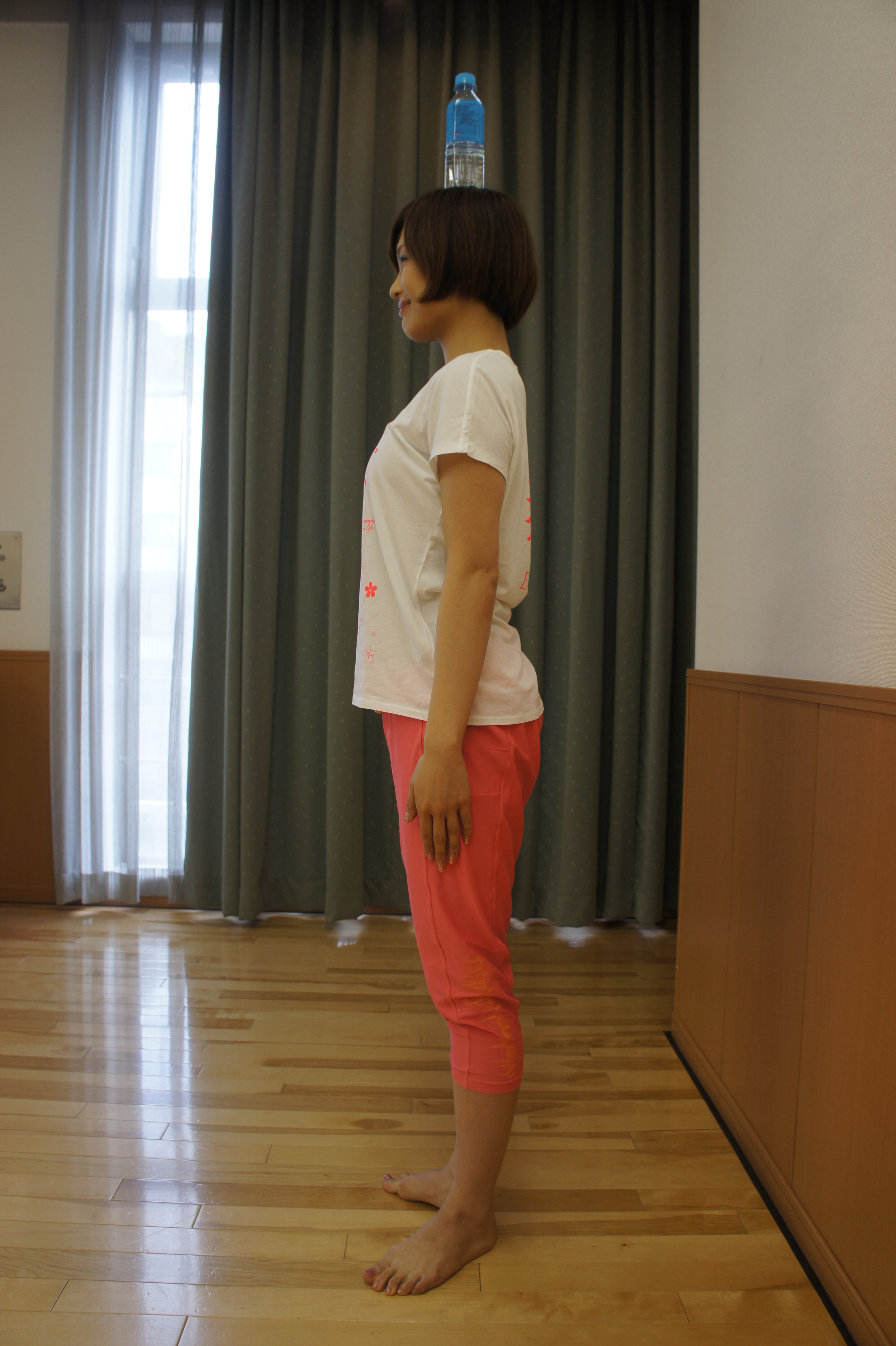 正しい姿勢で直立し、頭にペットボトルを乗せる