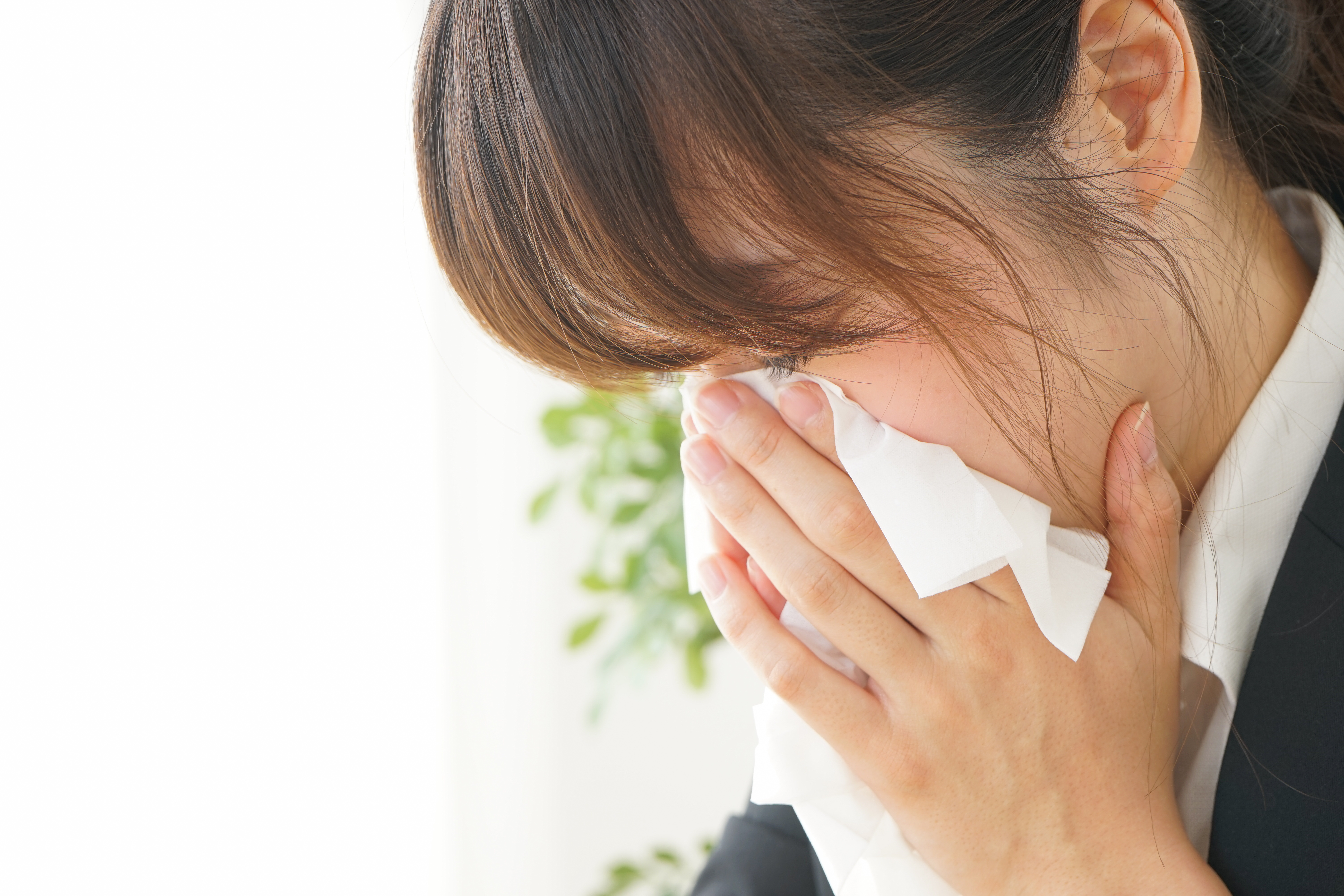 ティッシュで鼻をかむ若い女性
