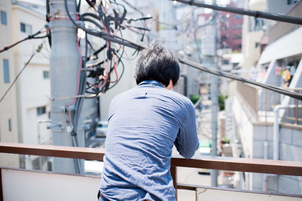 ベランダで考え込む男性