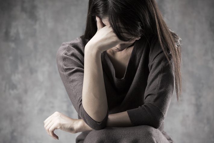 頭を抱える女性　悩む