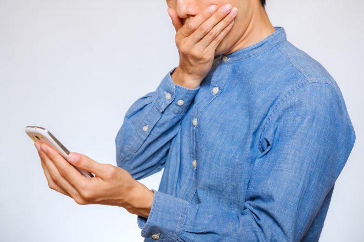 スマホを見て驚く男性
