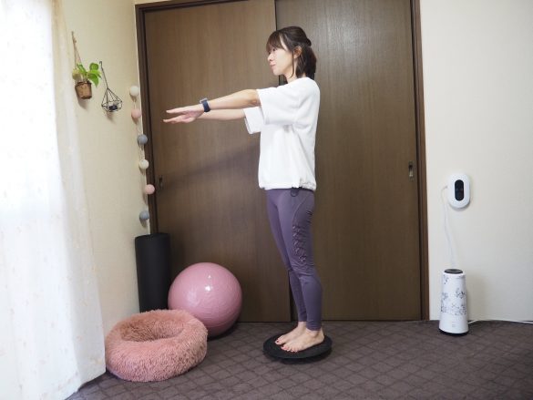 バランスボードの上に両脚で立ち、腕を肩の高さに持ち上げます