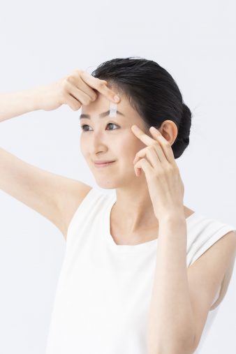 ③片手でまぶたを引き上げながら、まぶたを軽くしてテープを貼る。まばたきができる程度に。