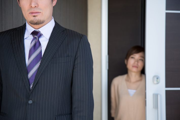 玄関で夫を送り出す妻