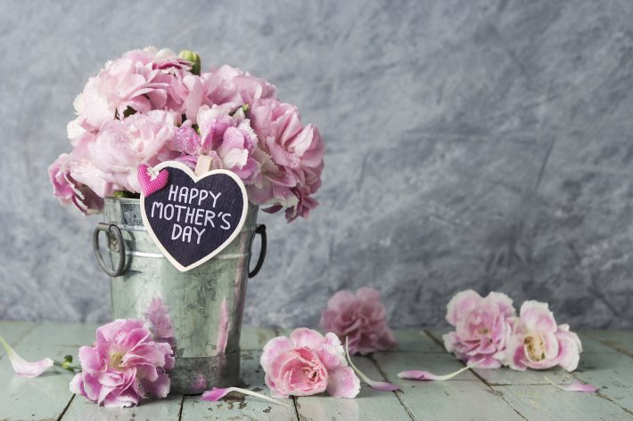 Pink carnation flowers in zinc bucket with happy mothers day letter on wood heart