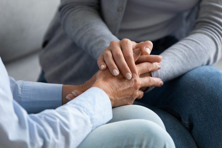 Young woman granddaughter hold old female grandma hand, closeup