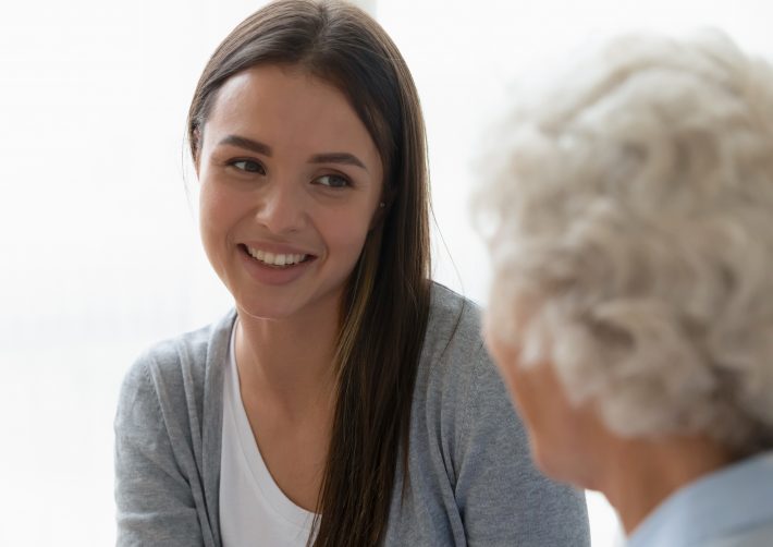 Happy young woman talking with mature mom at home