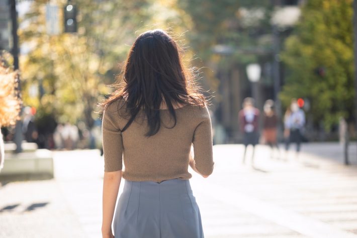 外を歩く働く女性の後ろ姿