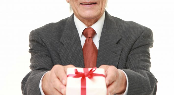 プレゼントを差し出すシニアのビジネスマン