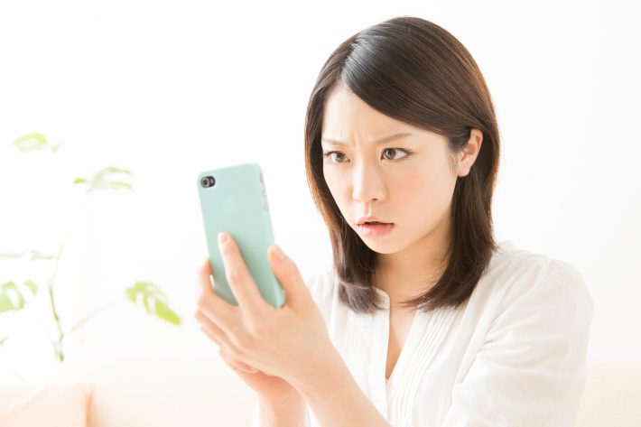 スマホを見て怒る女性