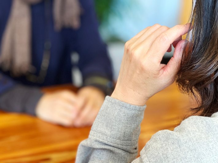 女性の正面で手を髪にやる女性