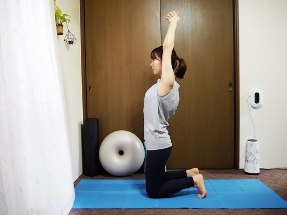 （1）床にひざ立ちになり、両腕を頭上に伸ばしたら指を組む。