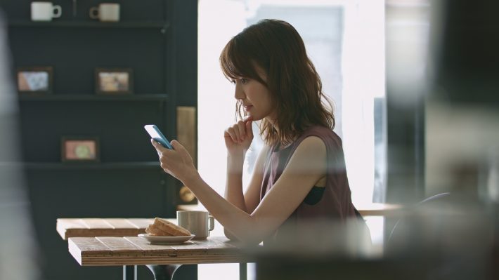 カフェでスマートフォンを見る女性