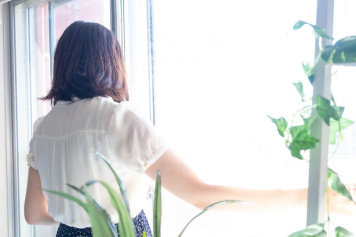 窓際に立つ女性の後ろ姿