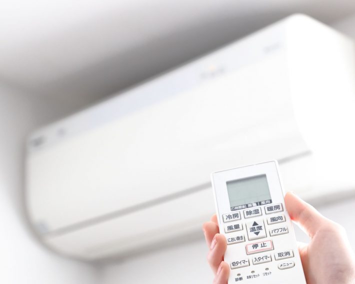 エアコンのリモコンを操作する女性の手