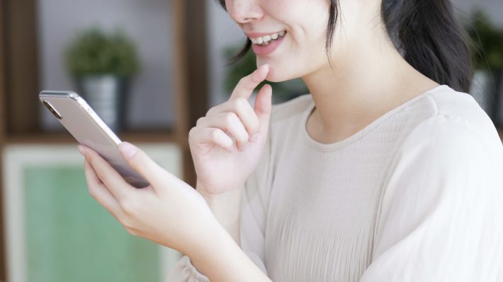 リビングでスマートフォンを見る若い女性