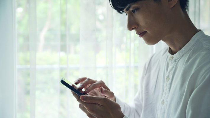 スマホを見て悩む男性