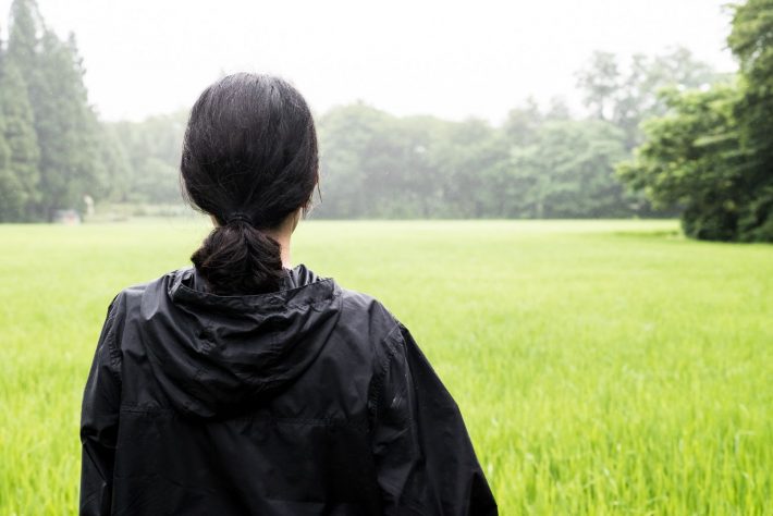田んぼを見つめる女性