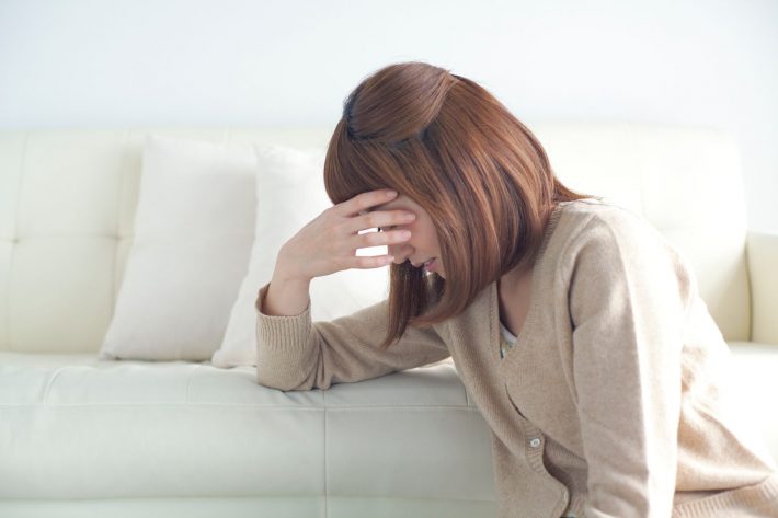 頭に手を当てる女性