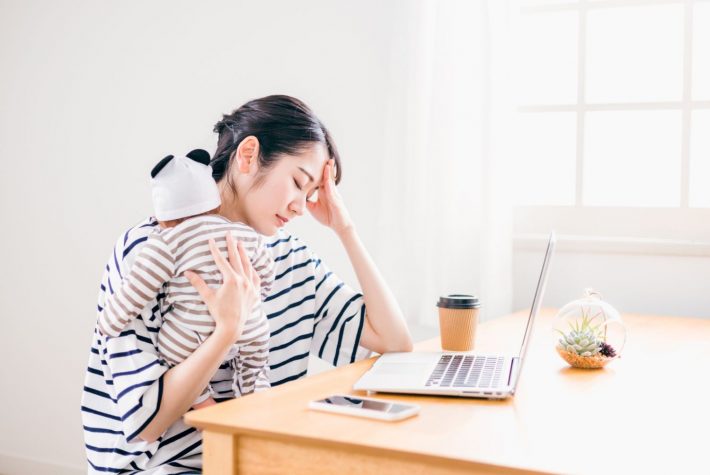 赤ちゃんの世話をしながら在宅ワークする女性