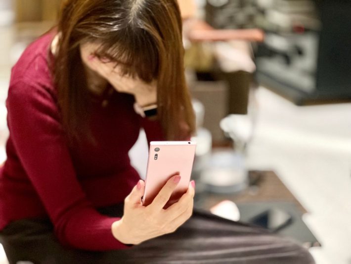 部屋でスマホを見て泣く女性