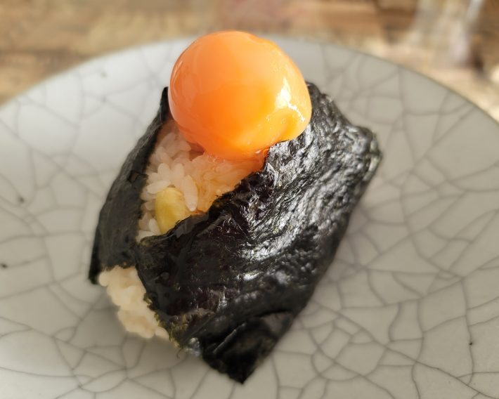 おにぎりの上で力強くきらめく卵黄醤油漬け