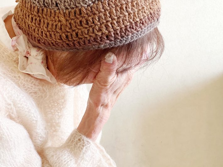 顔を手で覆う高齢女性