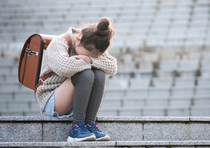 階段に座って泣く小学生