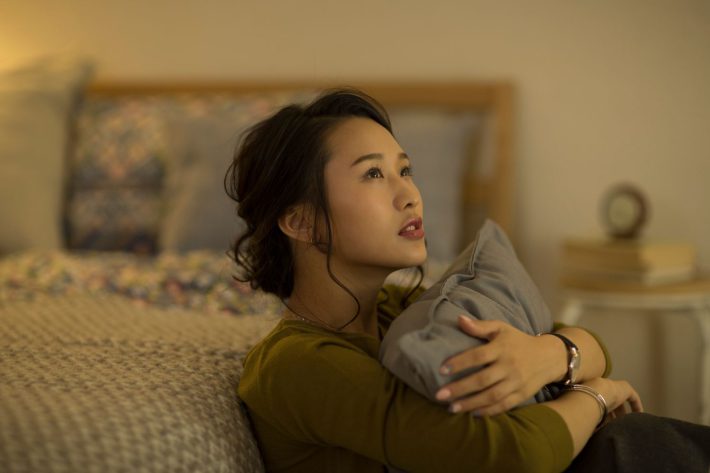 部屋で考え事をする女性