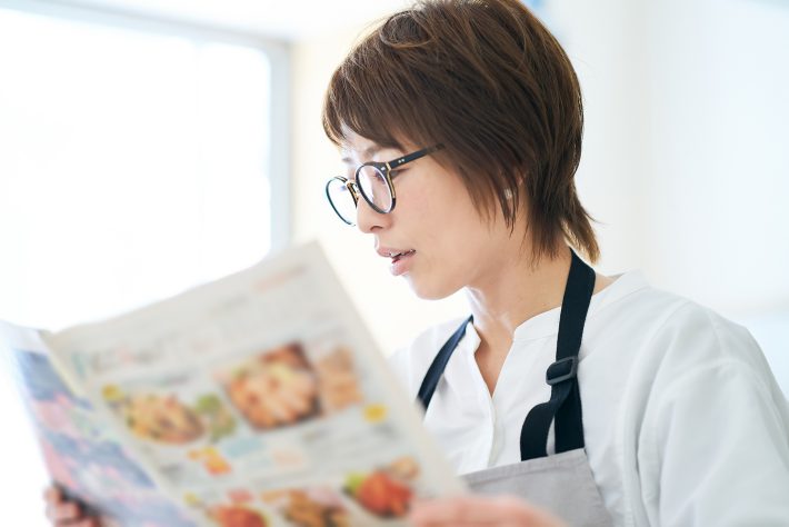 メガネをかけて広告チラシを見る女性