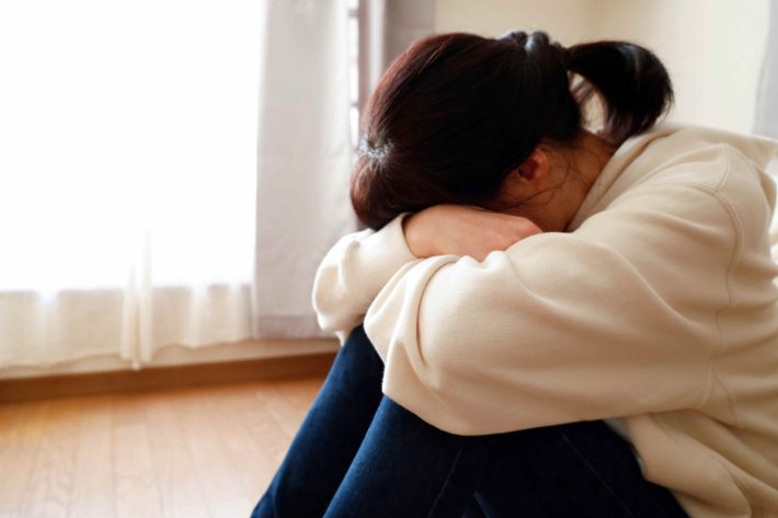 床に座って落ち込む女性