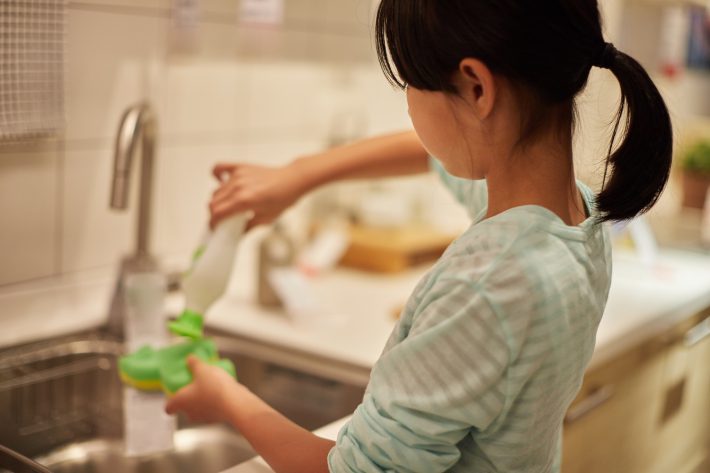 家のキッチンでお皿を洗う子ども