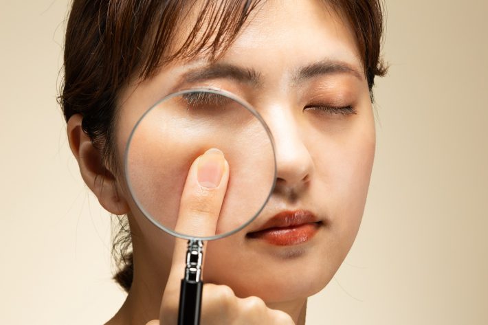 肌をルーペで拡大している女性