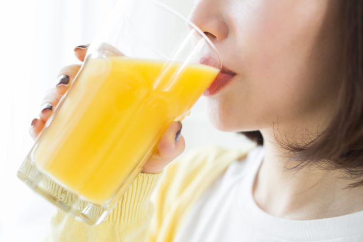 オレンジジュースを飲む女性
