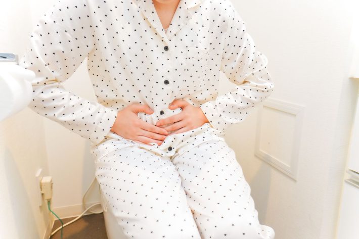 トイレでお腹をおさえる女性