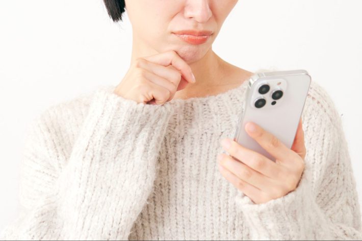 スマートフォンを持って困る女性　白背景