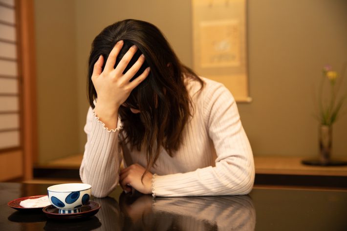 和室で頭を抱える女性
