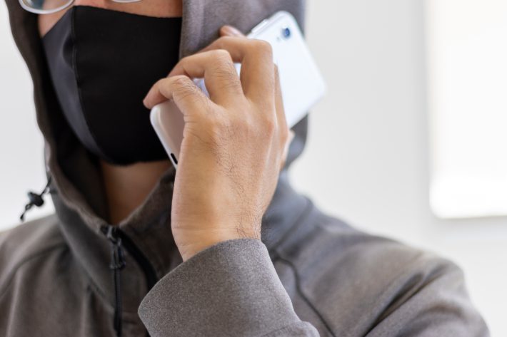 スマートフォンで電話をする顔を隠した怪しい男性