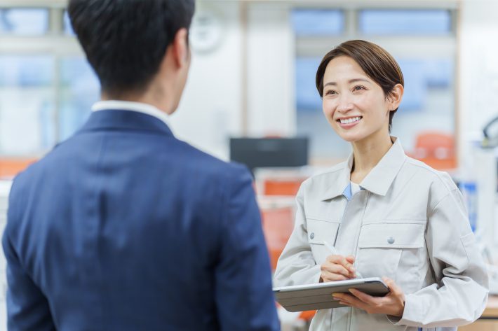 事務所で打ち合わせをするビジネスマンと女性作業員