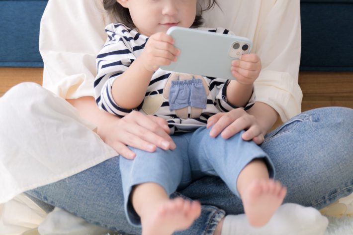 子どもと一緒にスマホを見る母親　正面