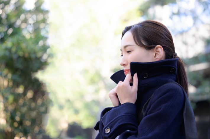 寒くてコートの襟をたてる女性