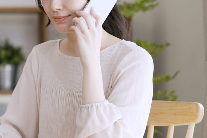 電話をしながらラップトップを使う若い女性