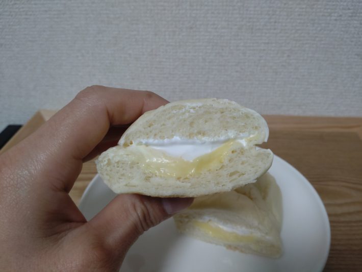 白生コッペパン（カスタード＆ホイップ）を見せる手
