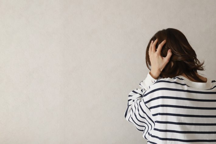 頭を抱えて落ち込む女性