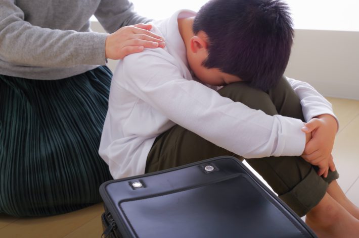 辛そうな小学生の男の子とその母親