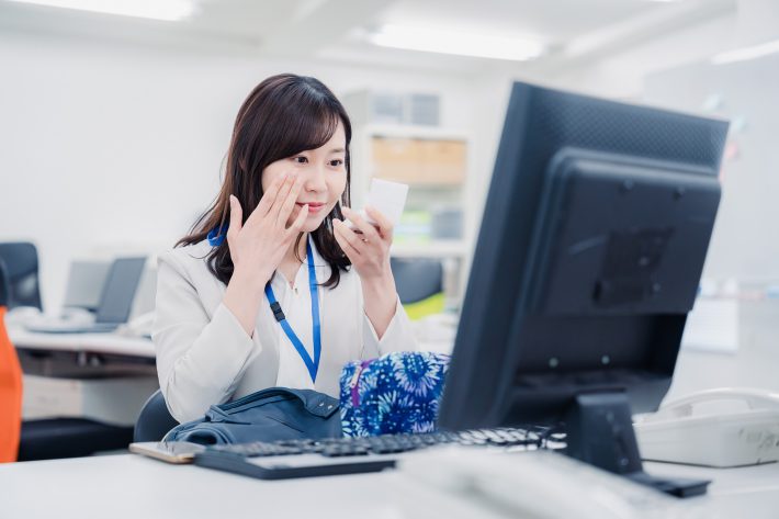 職場でメイクをチェックする女性