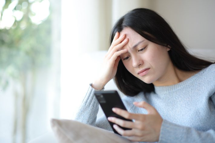 スマホを見てショックを受ける女性