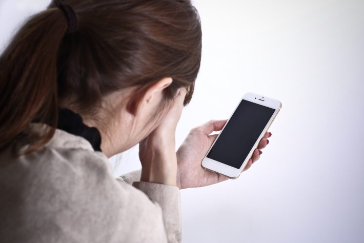 スマホを手にショックを受ける女性