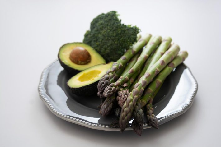 お皿の上に並べられたアボカド、ブロッコリー、アスパラガス