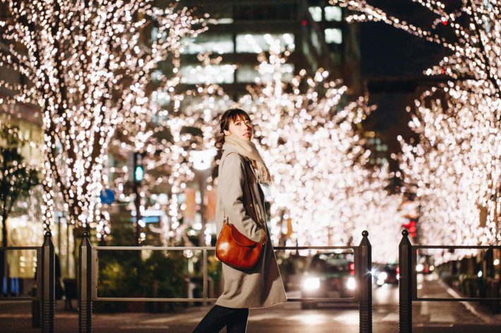 イルミネーションが輝く道を歩く女性